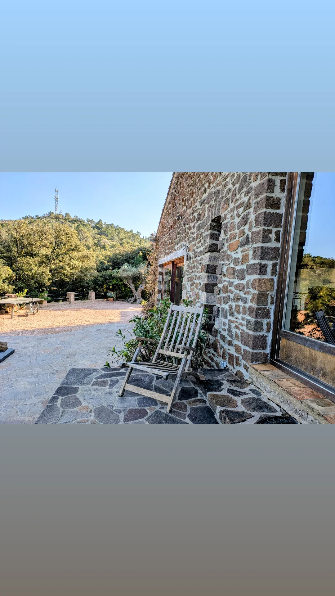 Terrasse en pierre le long de la maison, ouverte sur le paysage
