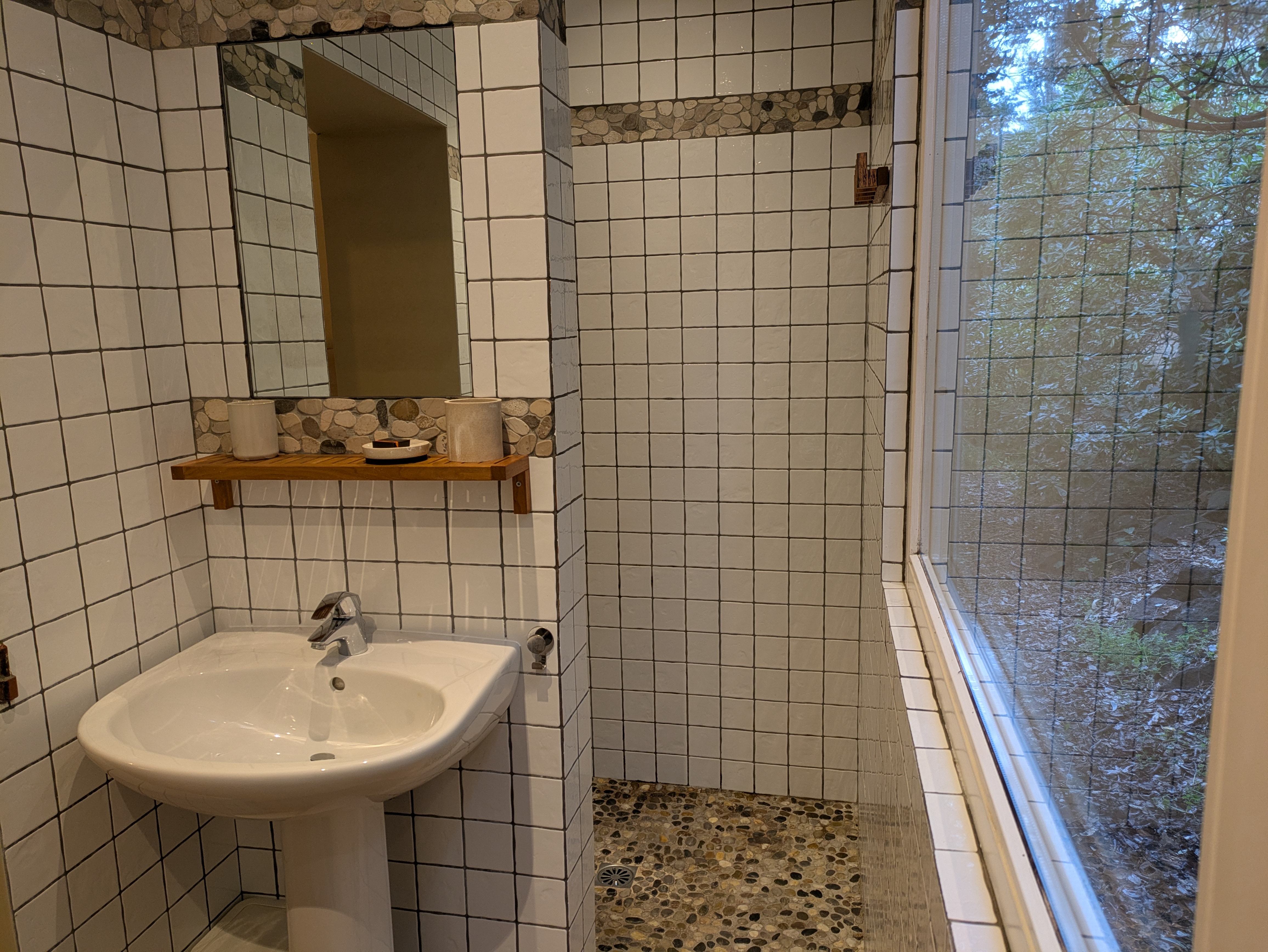 Salle d’eau lumineuse avec douche ouverte sur les bois